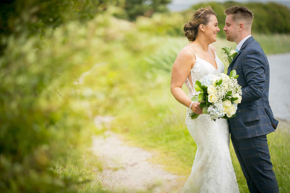 Bride and groom smiling outdoors by a path