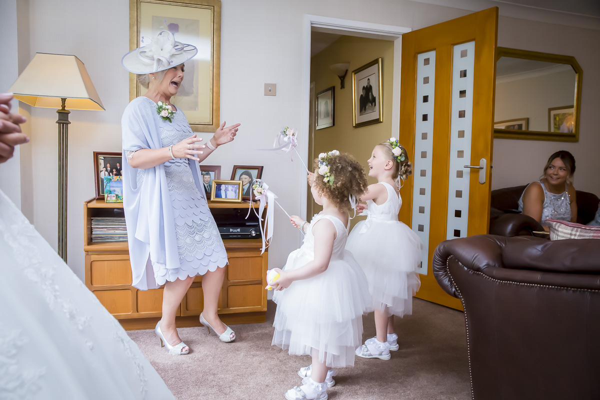 Excited children in dresses play with woman indoors.
