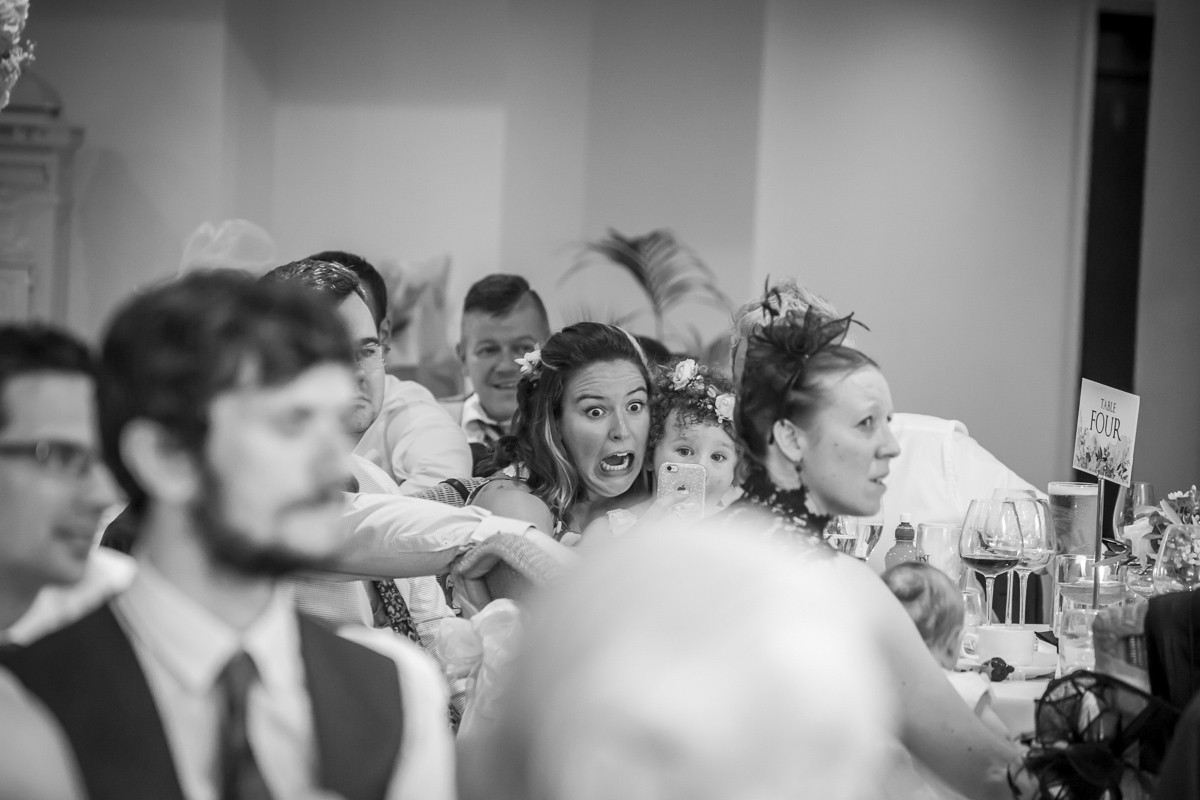 Wedding guests surprised by something off-camera.