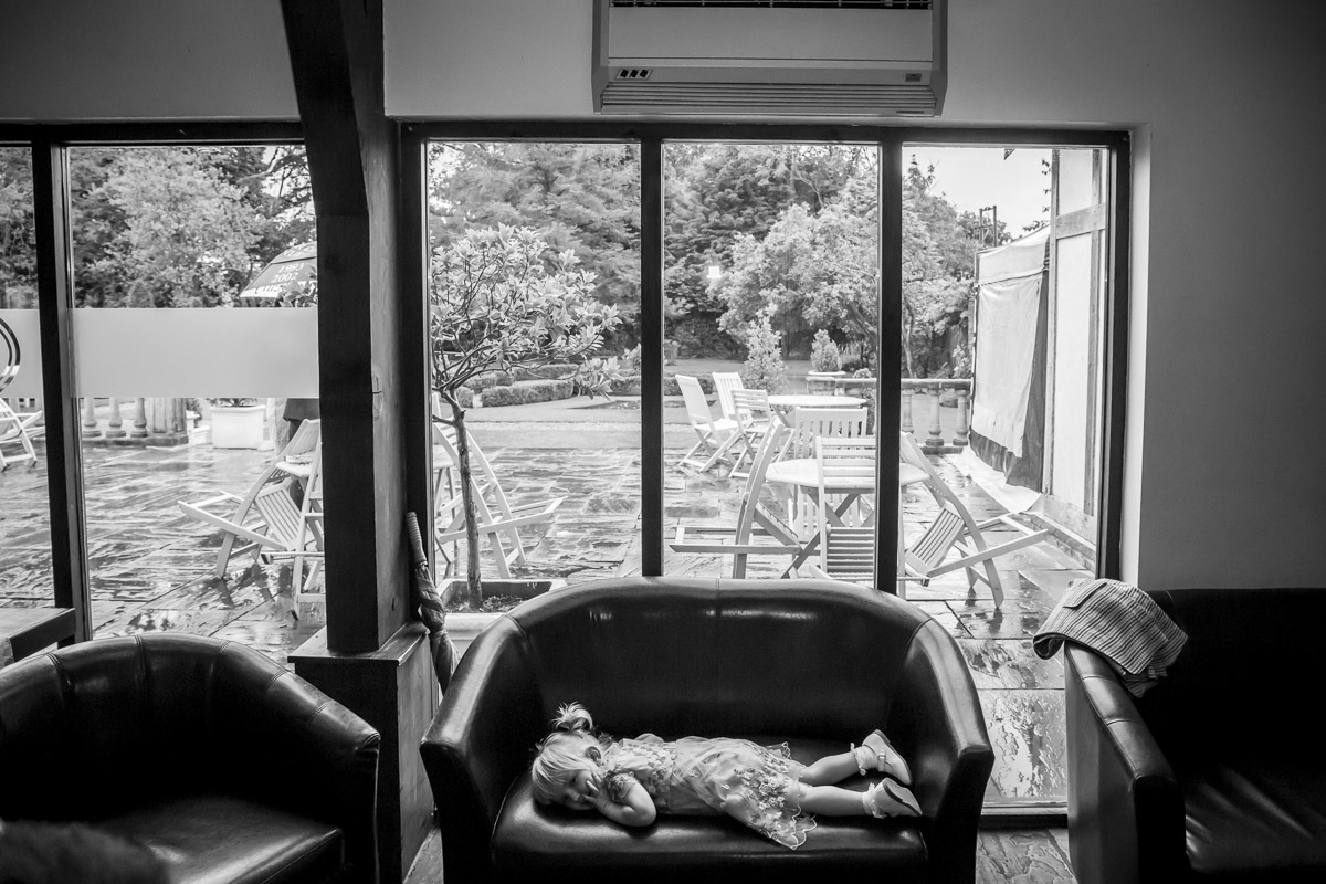 Child sleeping on a sofa indoors, garden view.