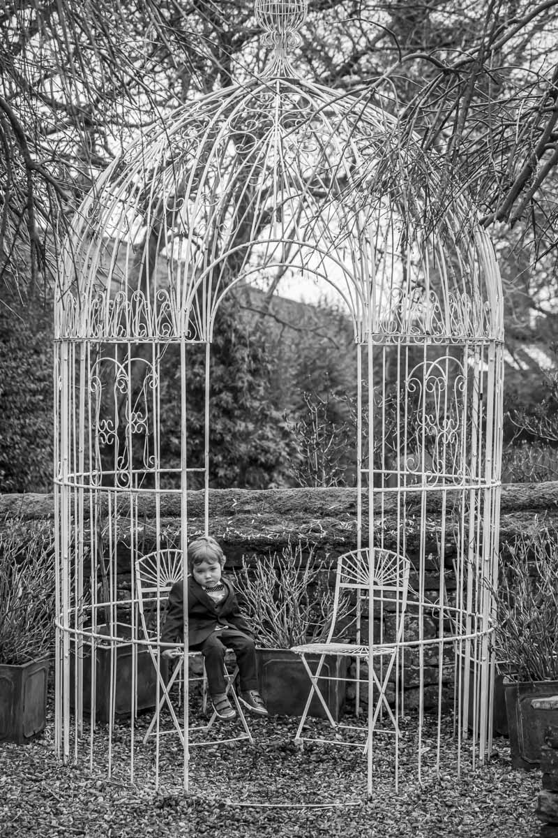 Child sitting in large decorative metal gazebo.