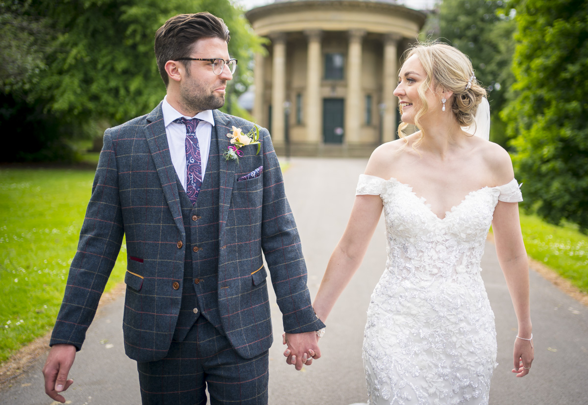 Bride and groom holding hands outdoors.