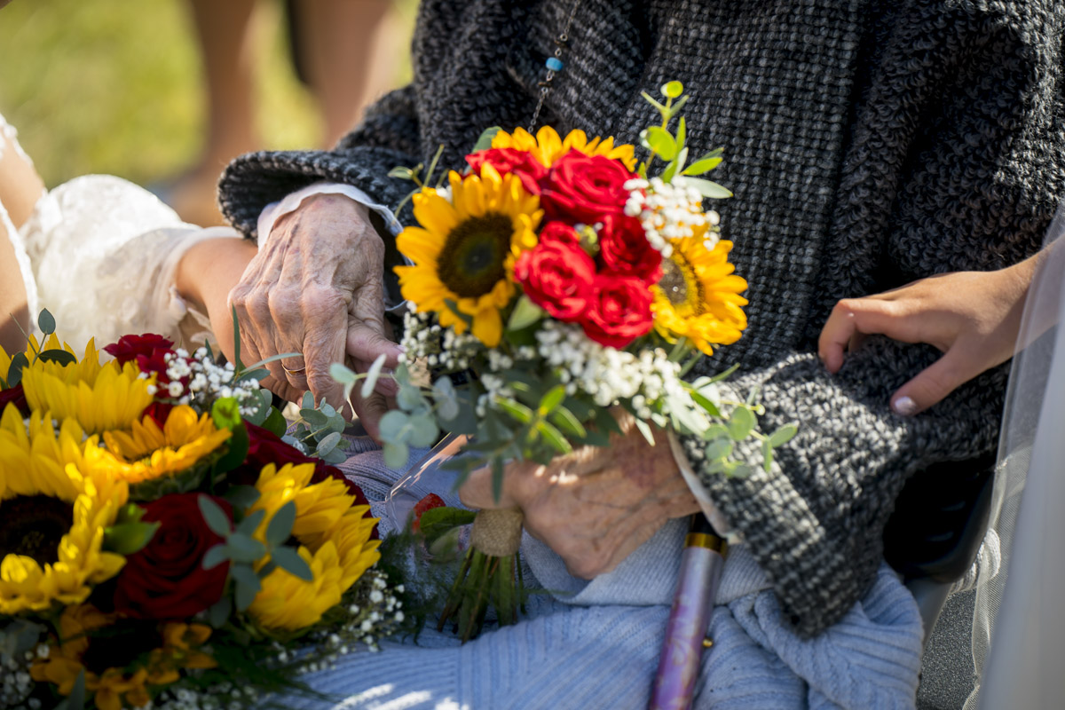 Elderly hands holding bright sunflower bouquet.
