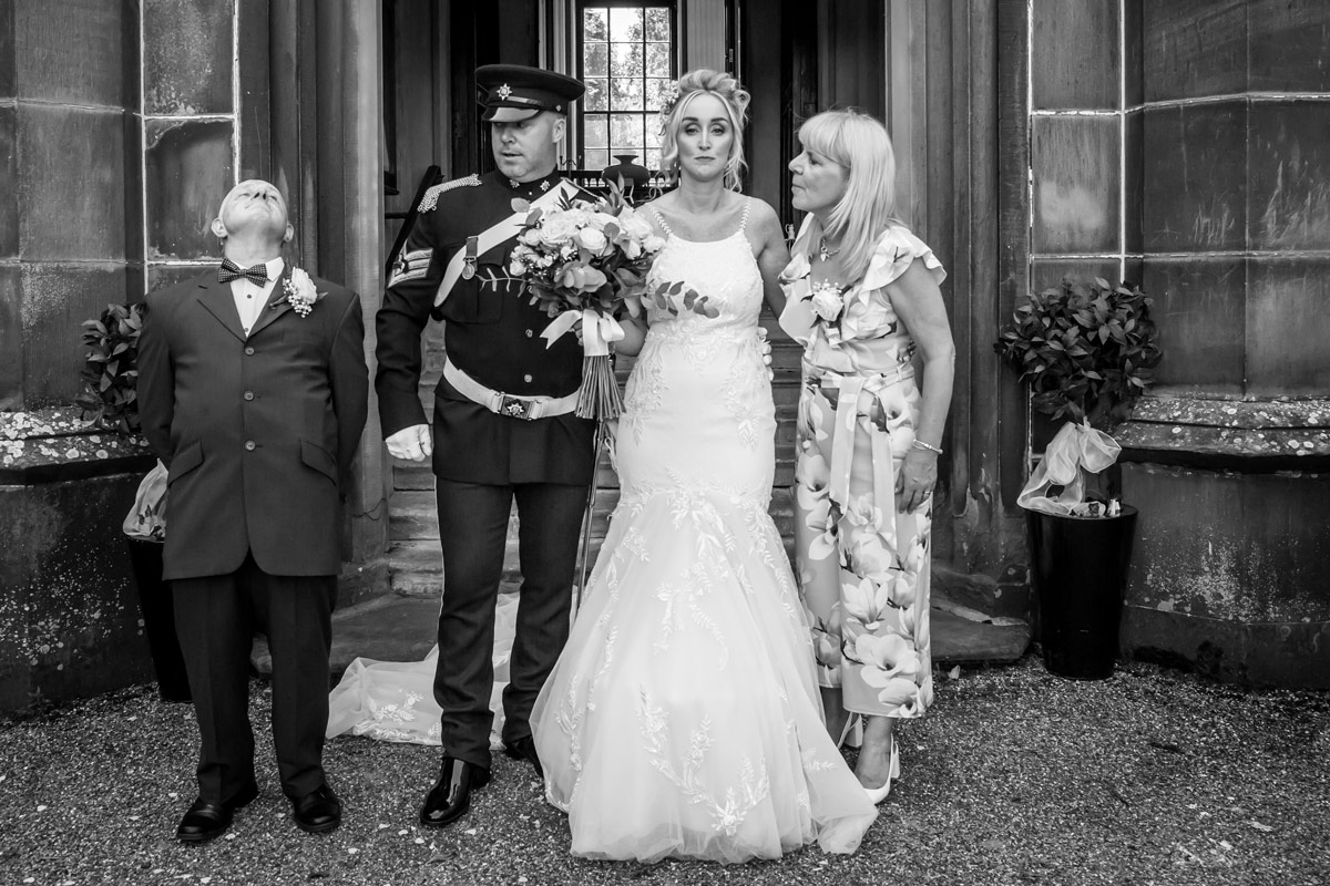 Wedding group photo in front of building entrance.