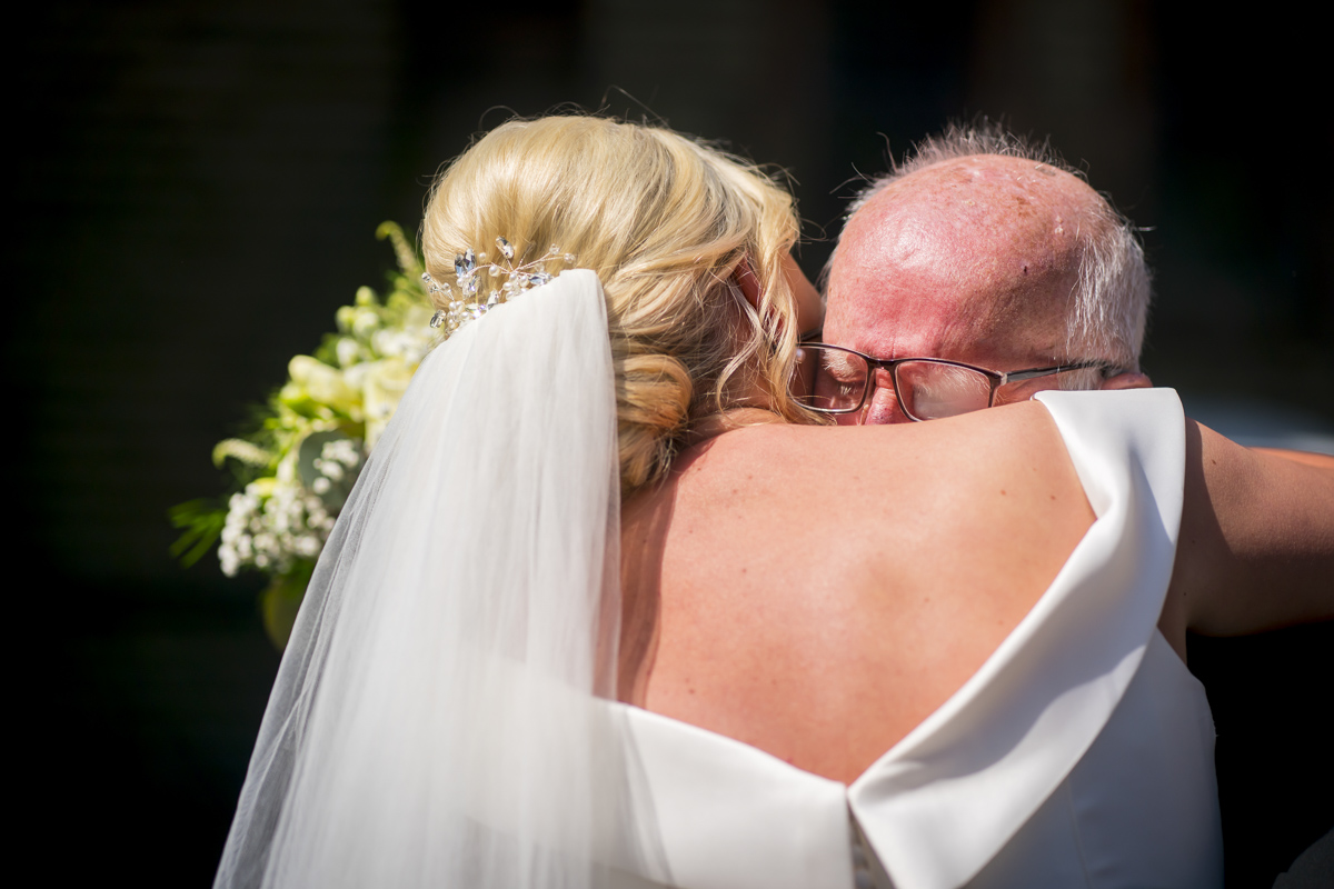 Bride hugging older man at wedding ceremony.