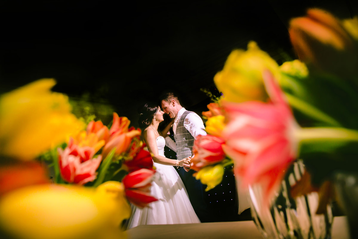 Bride and groom smiling surrounded by flowers.