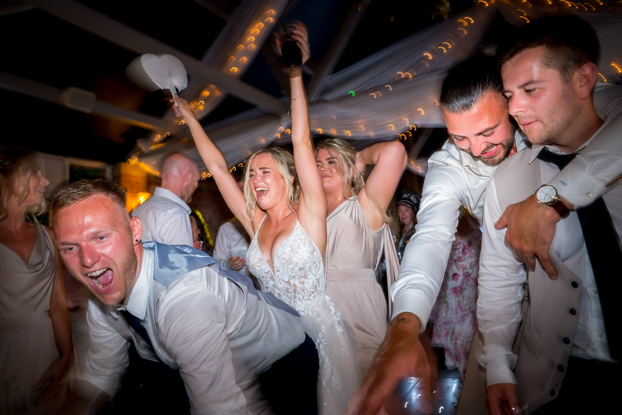 People dancing energetically at a wedding celebration.