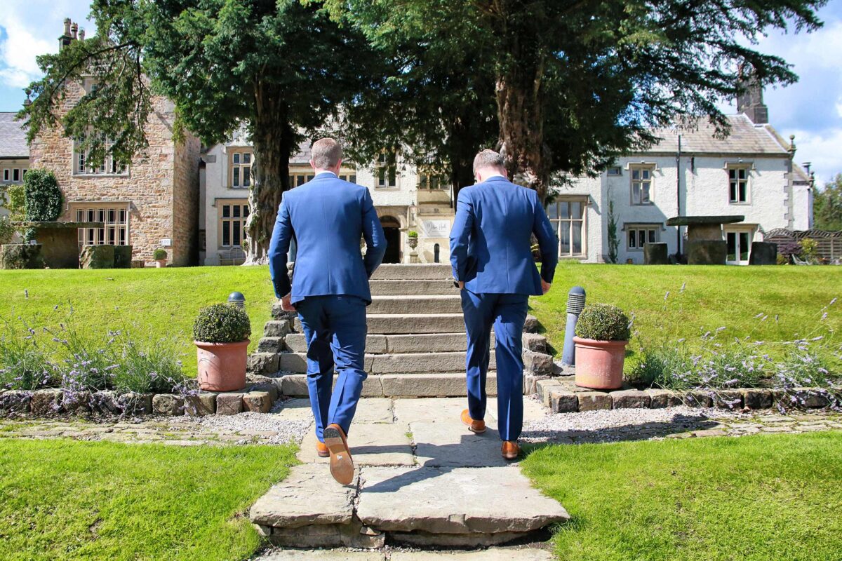 Two men in suits walk towards large house