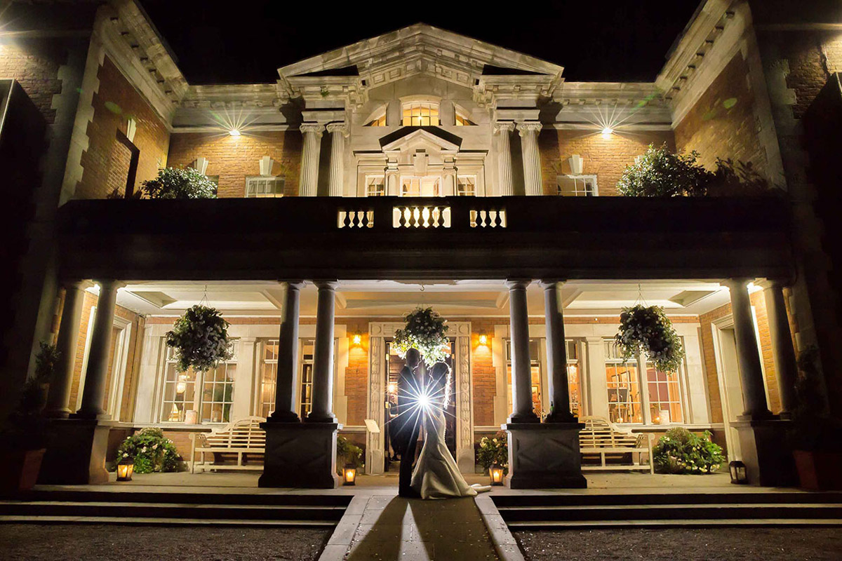 Couple at night in front of lit building.