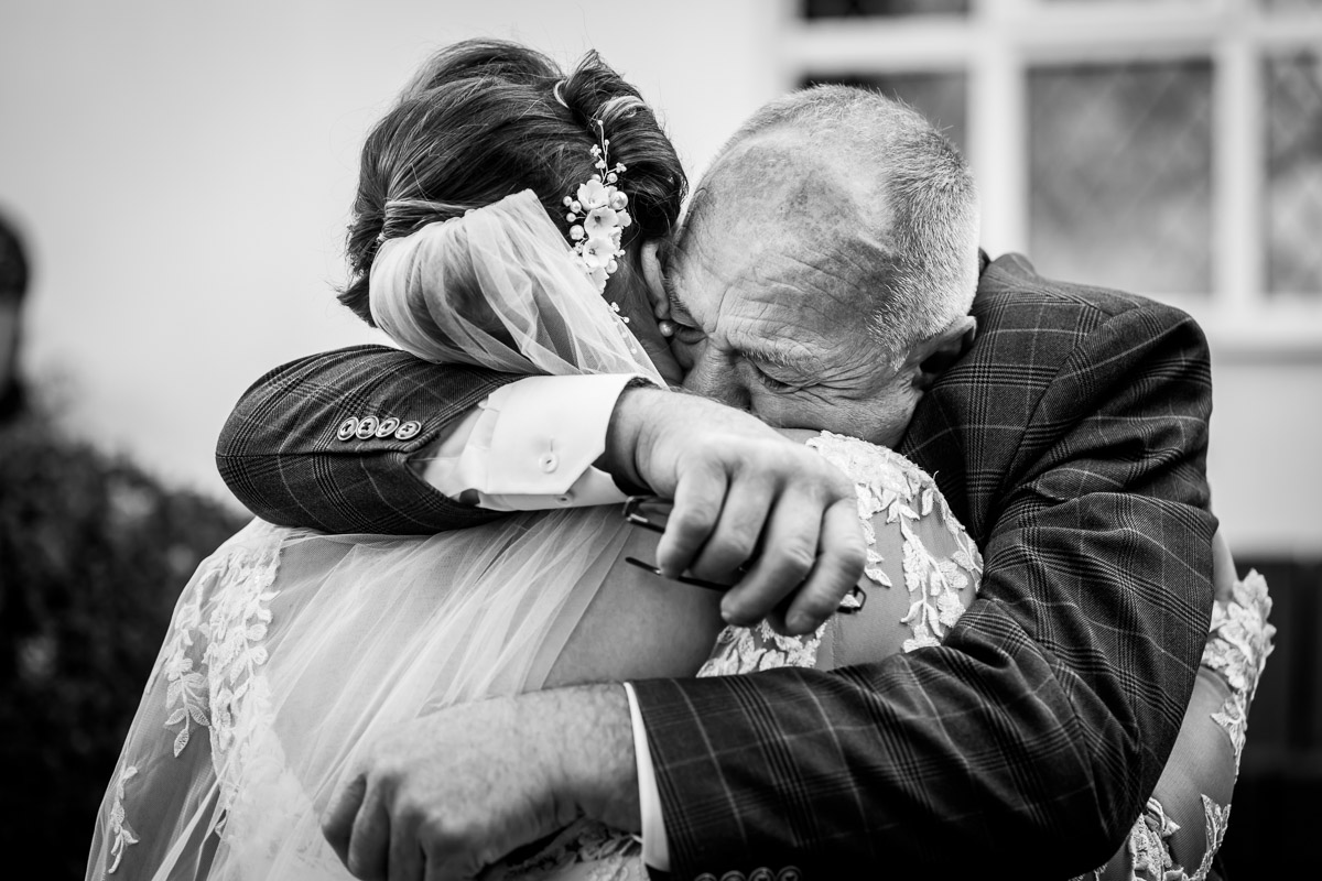 Emotional wedding embrace between bride and older gentleman.