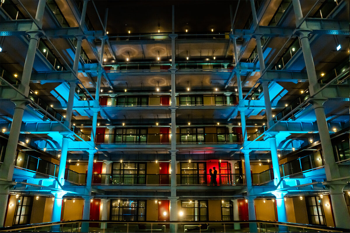 Colourful multi-story building interior with silhouetted figures.