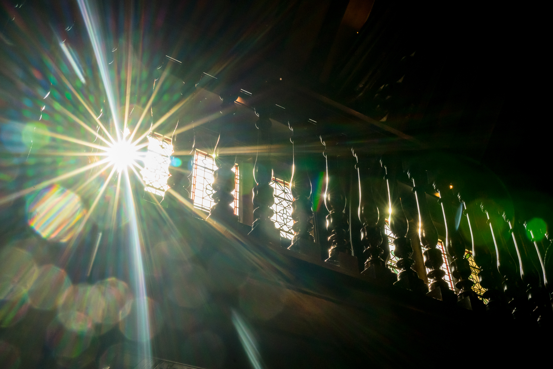 Sunlight streaming through window with wooden balusters.