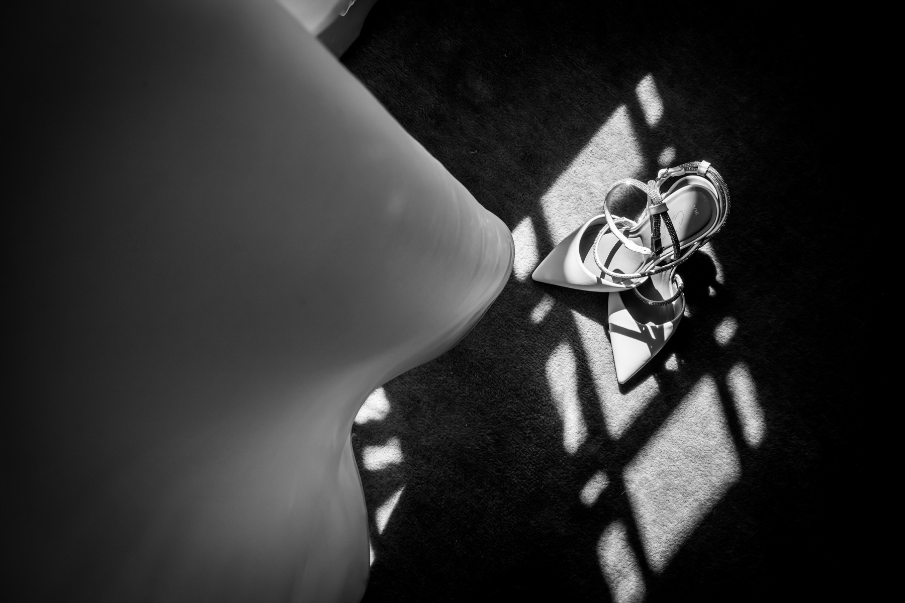 Bride's dress and shoes in sunlight pattern.