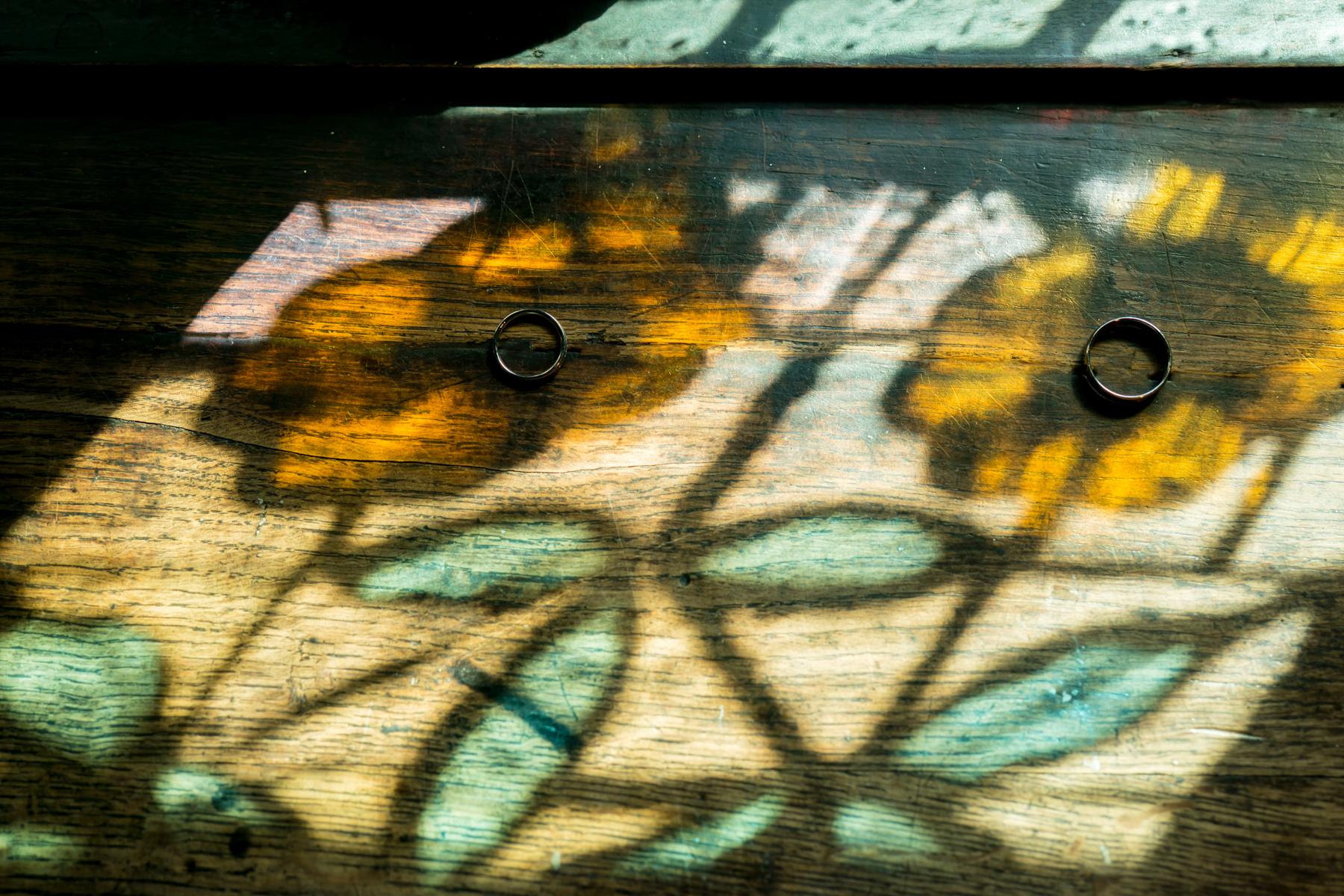 Rings on table with floral stained glass shadow.