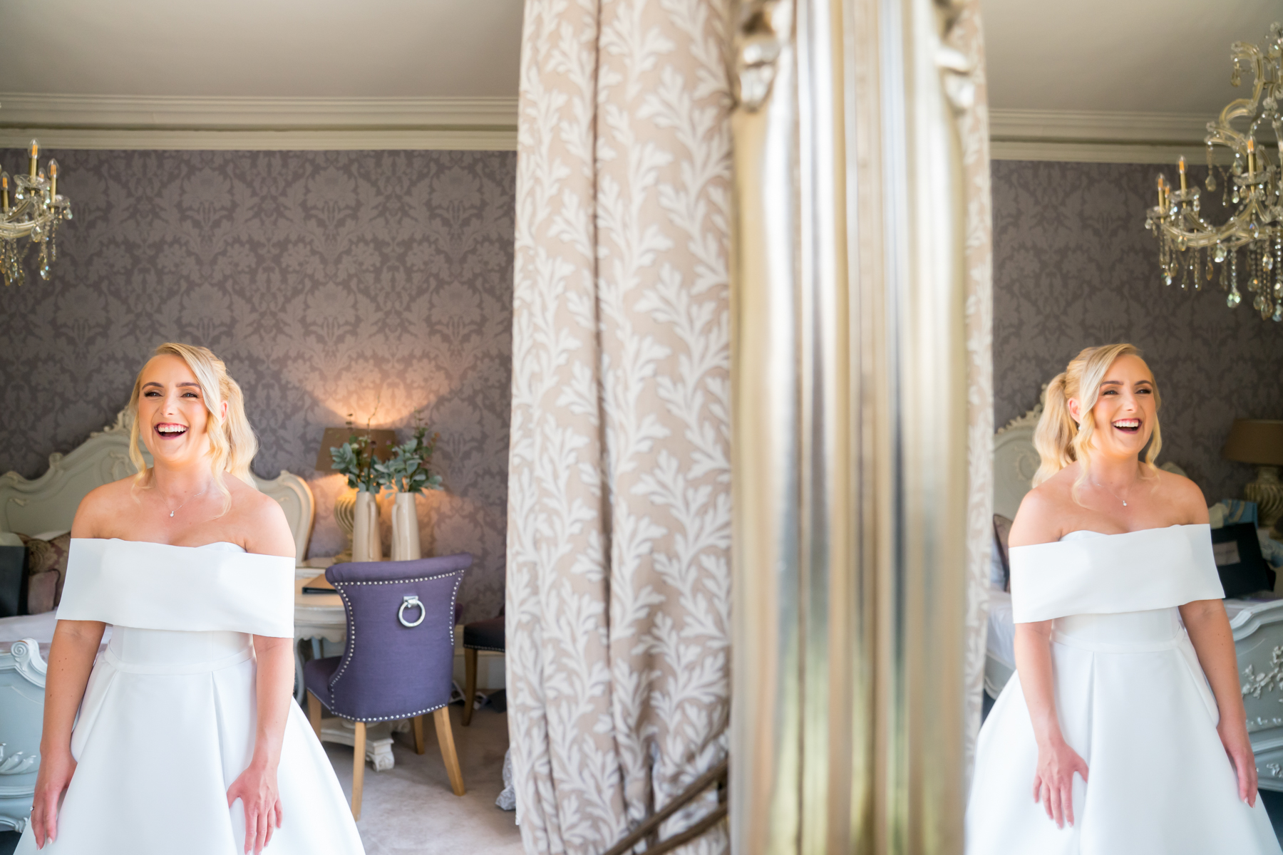 Bride smiling in elegant white gown indoors.