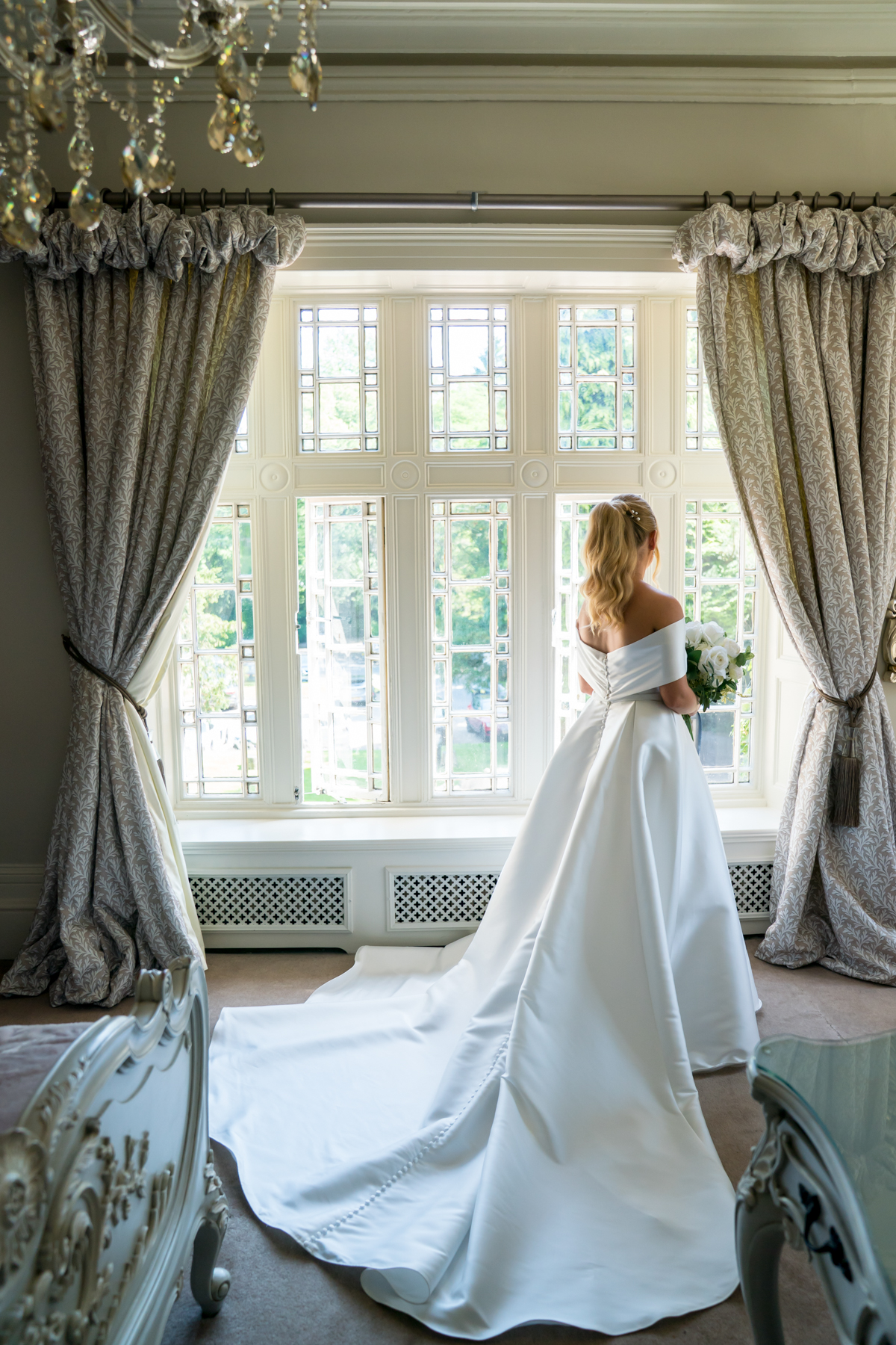 Bride in elegant gown looking out window