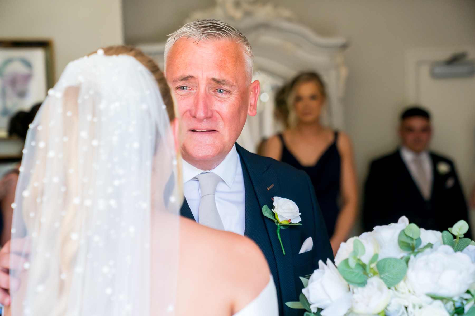 Emotional father with bride in wedding dress.