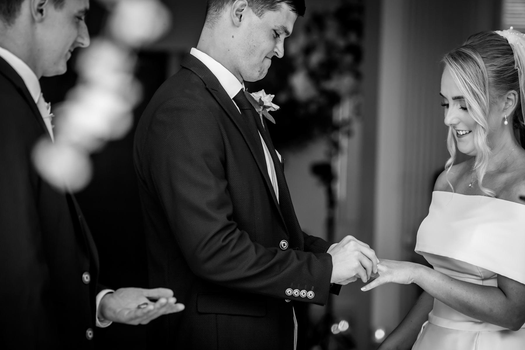 Groom placing ring on bride's finger during wedding.