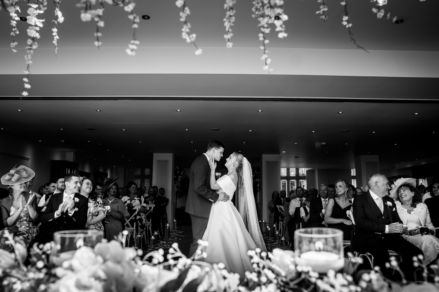 Bride and groom smiling during wedding ceremony with guests.