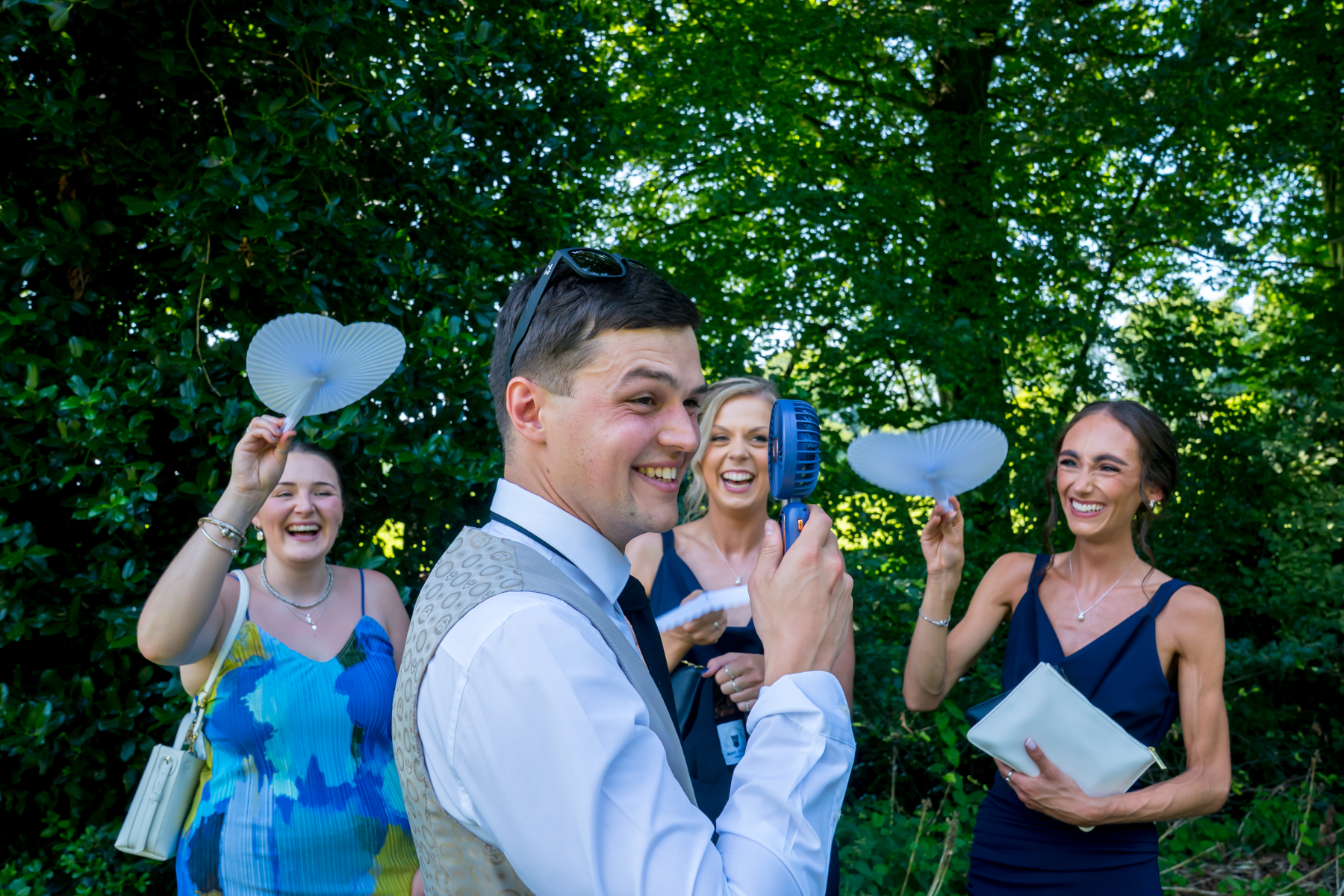Smiling people cooling with fans outdoors.