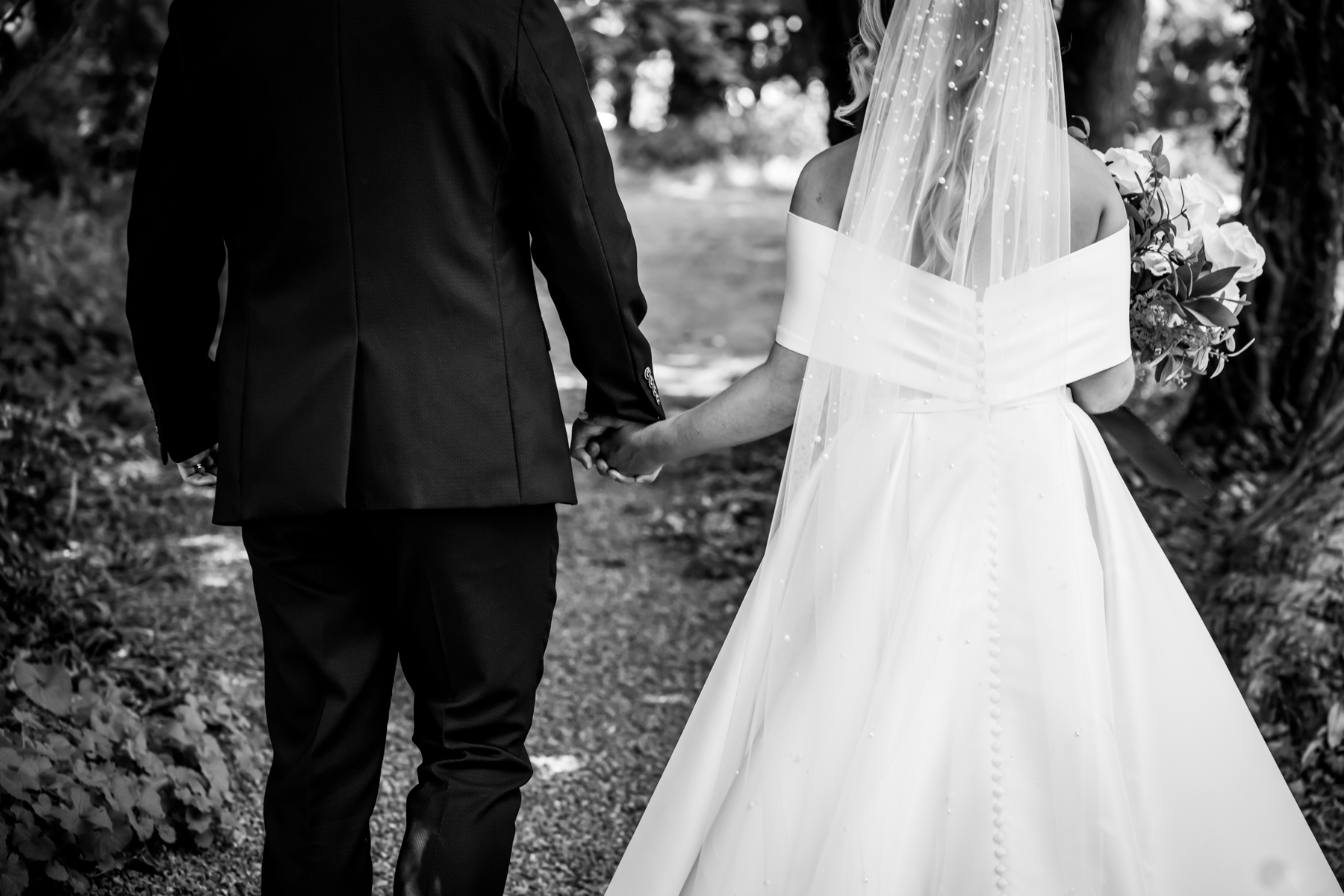Bride and groom holding hands, walking outdoors