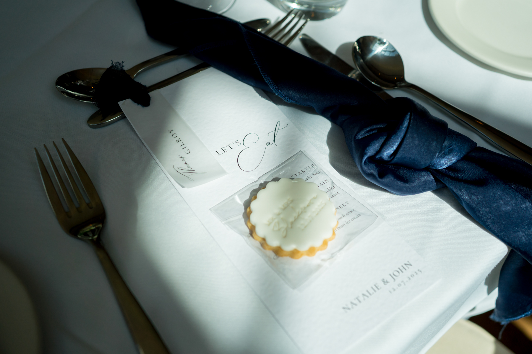 Wedding table setting with menu and wrapped cutlery.