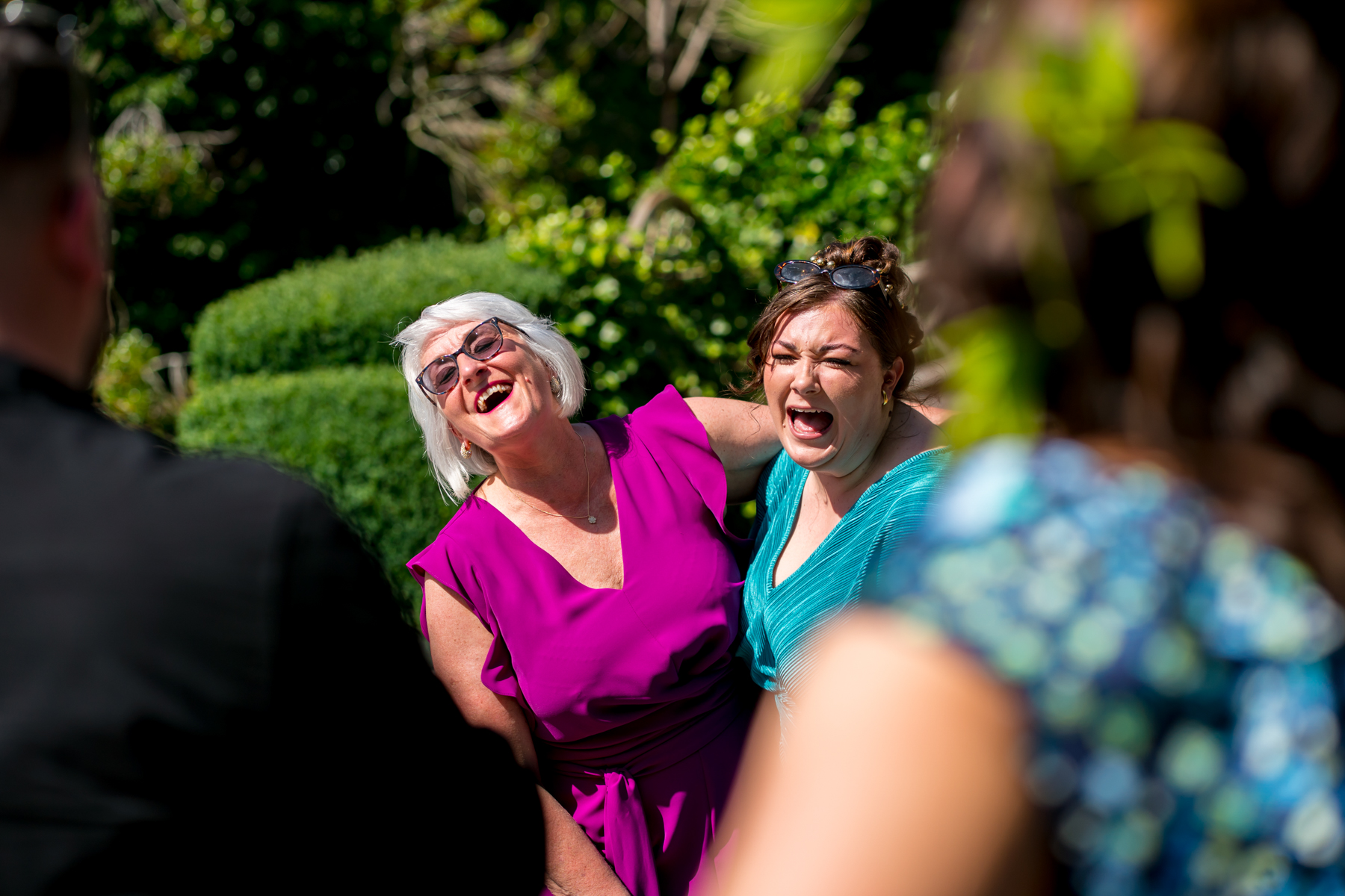 Two women laughing outdoors at a gathering.