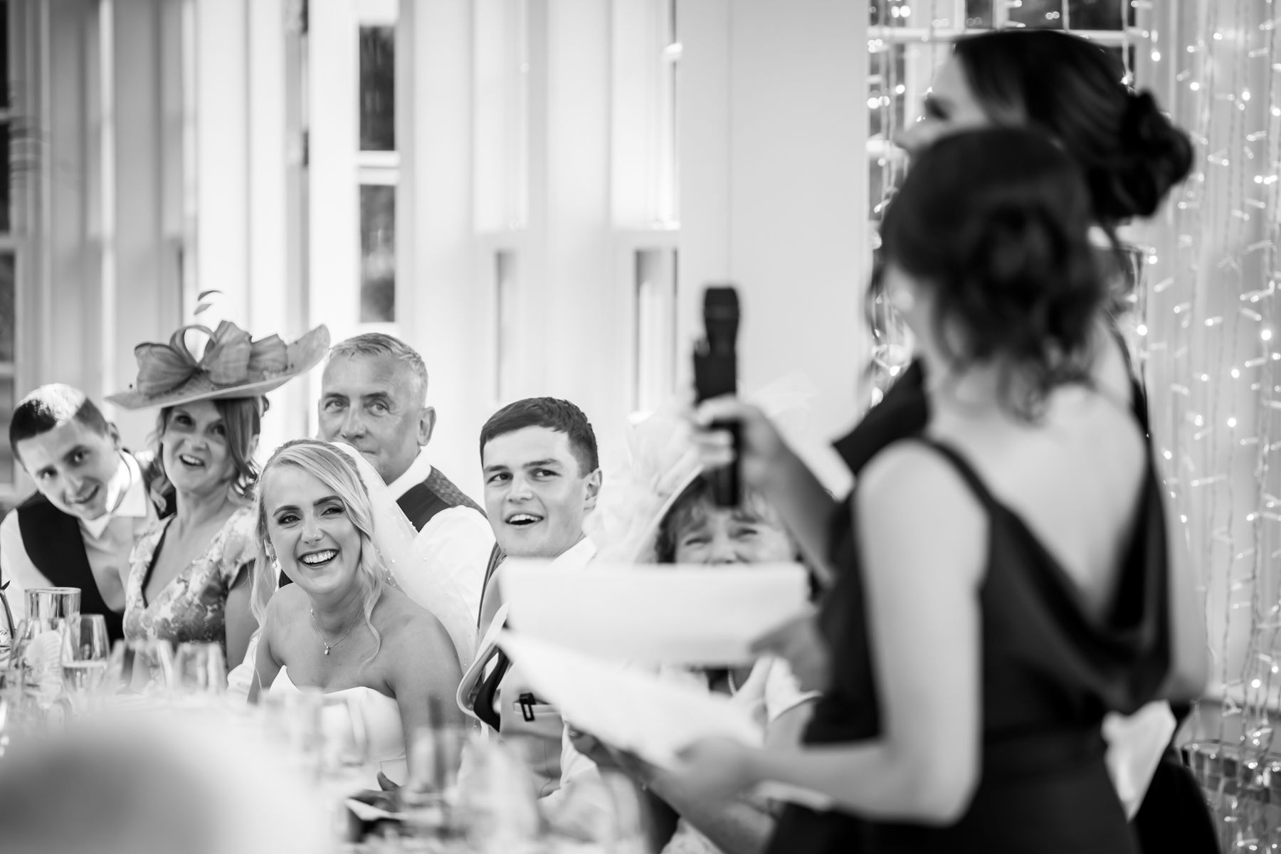 Wedding party smiling during reception speech.