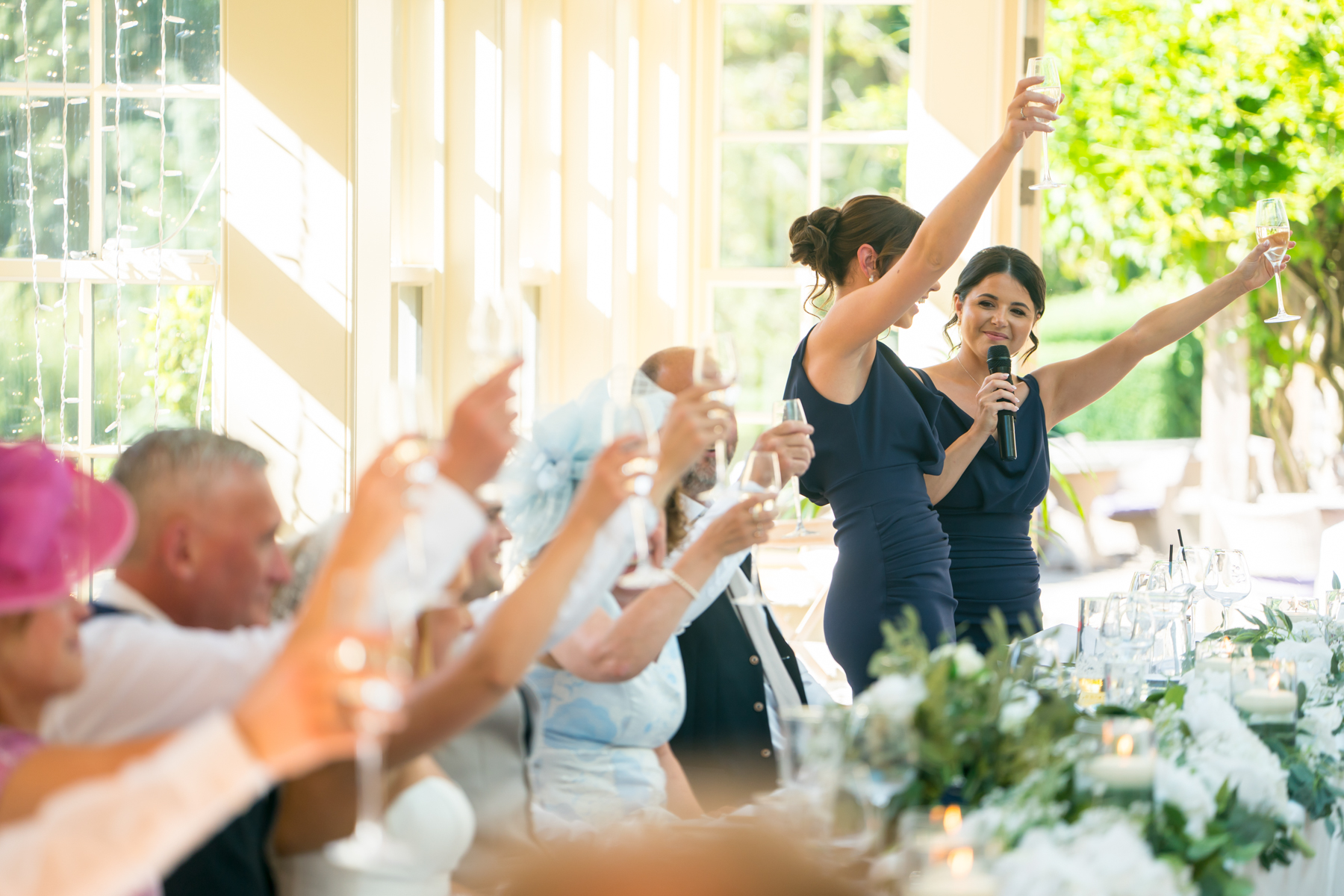 Wedding speech toast with raised glasses indoors.
