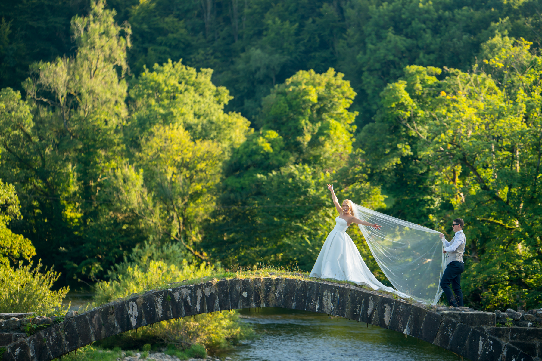Bride and groom on idyllic stone bridge.