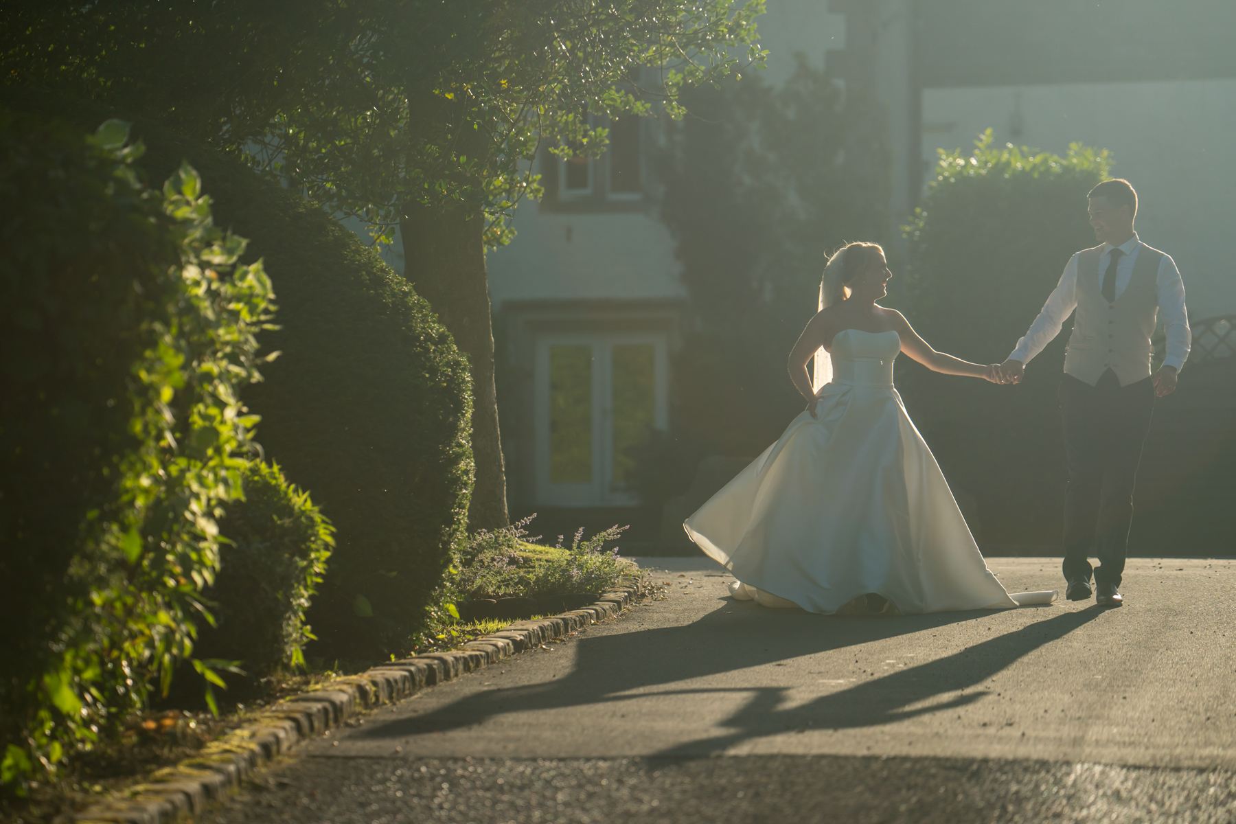Wedding couple walking in garden during sunset