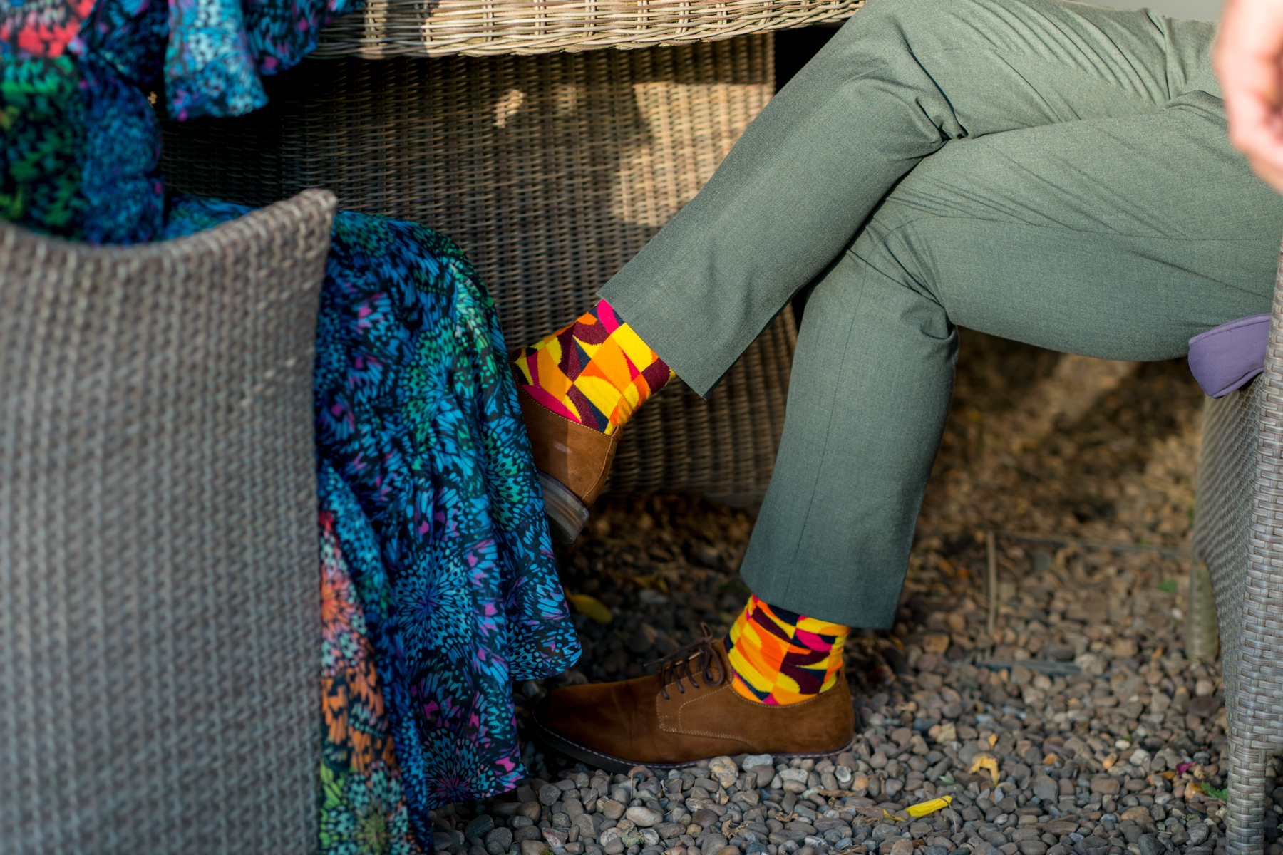 Colourful socks and chic trousers under a table.