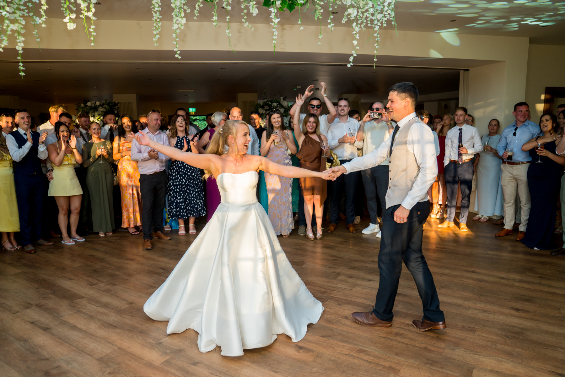 Bride and groom dance surrounded by guests.