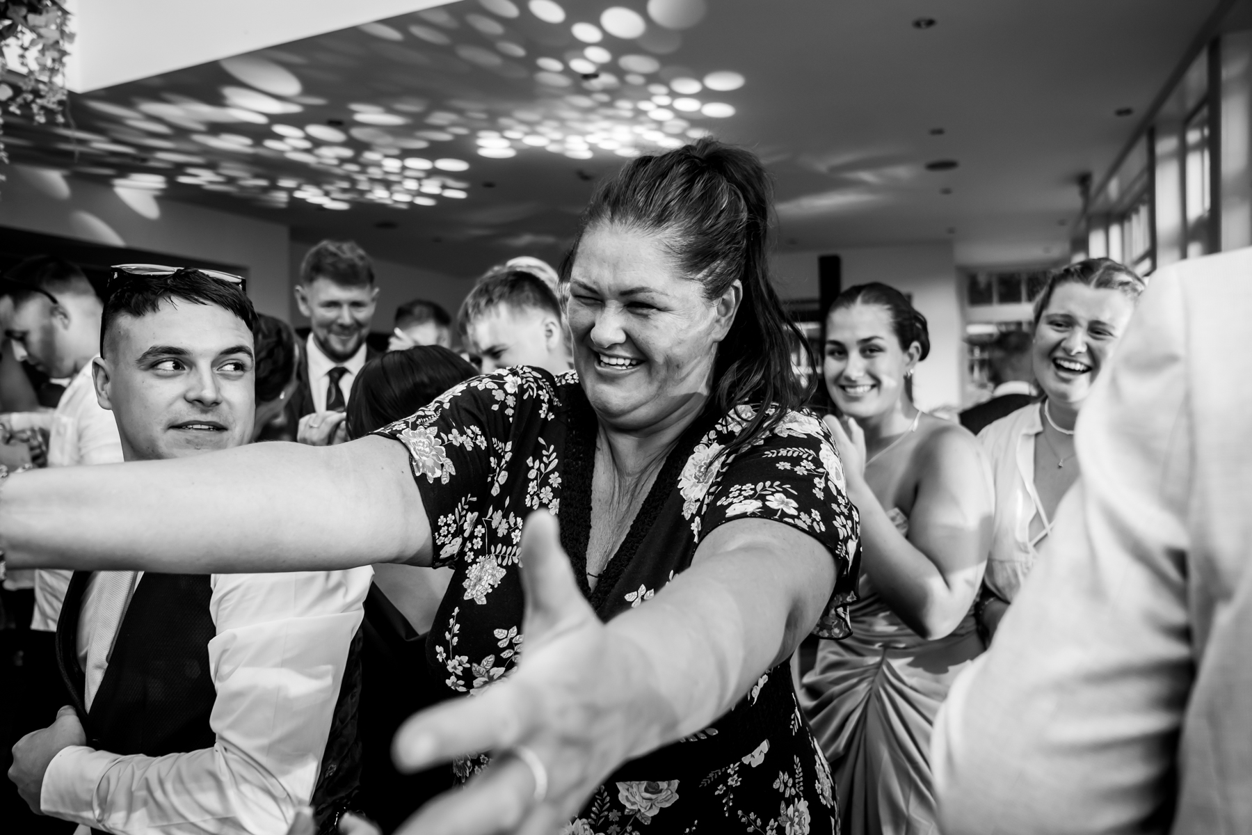 Joyful wedding celebration with smiling guests dancing.