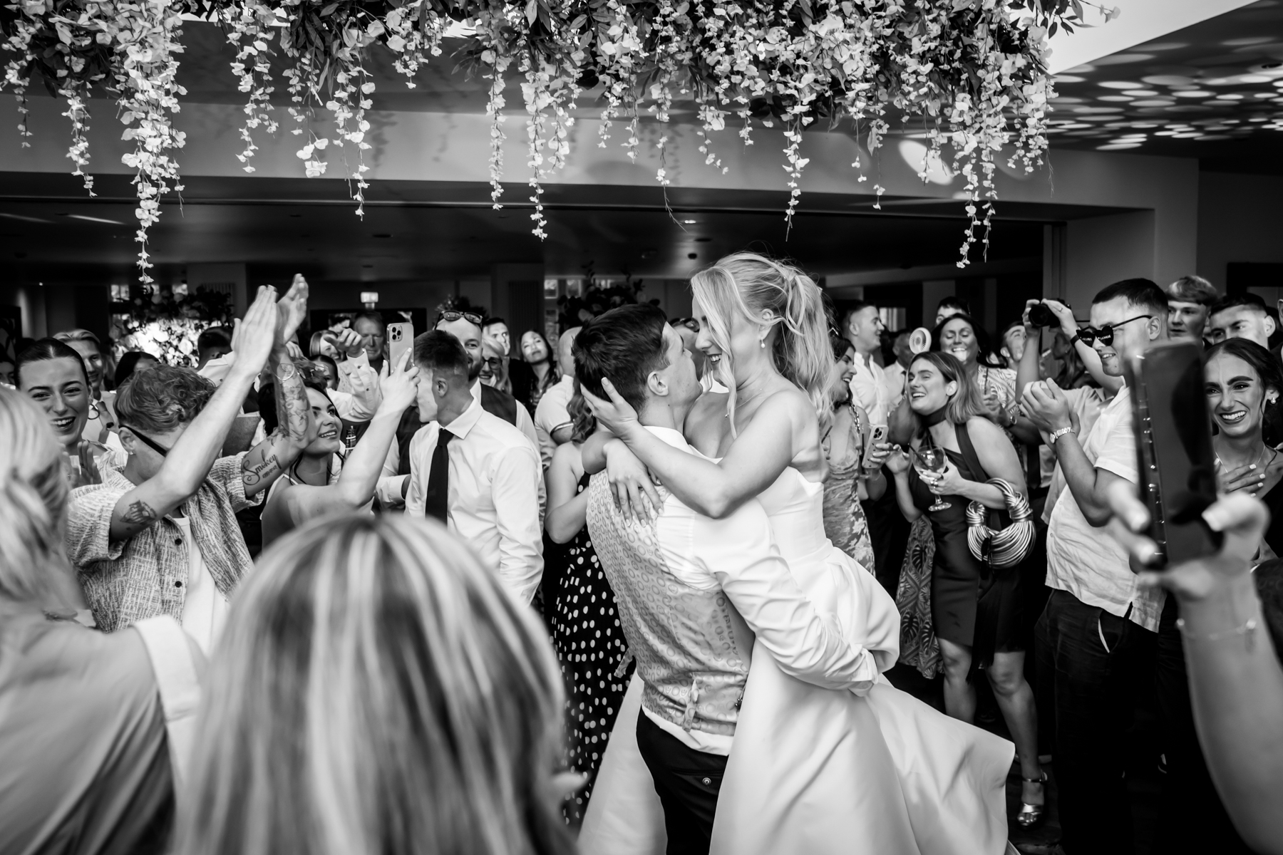 Bride and groom kiss at lively wedding reception.