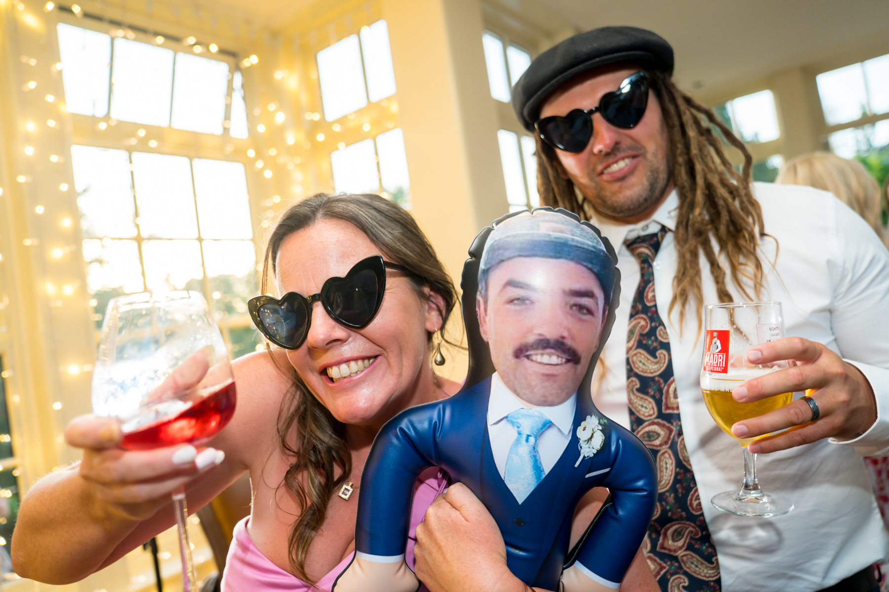 Smiling people with drinks and inflatable figure.