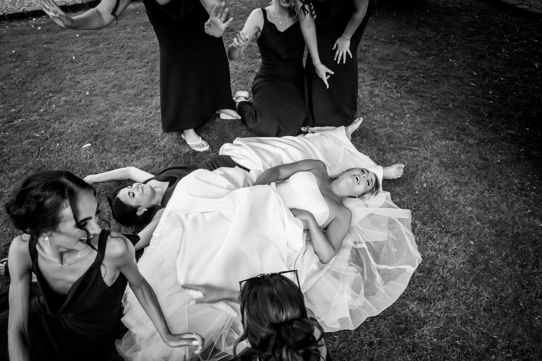 Women laughing on grass in formal dresses.