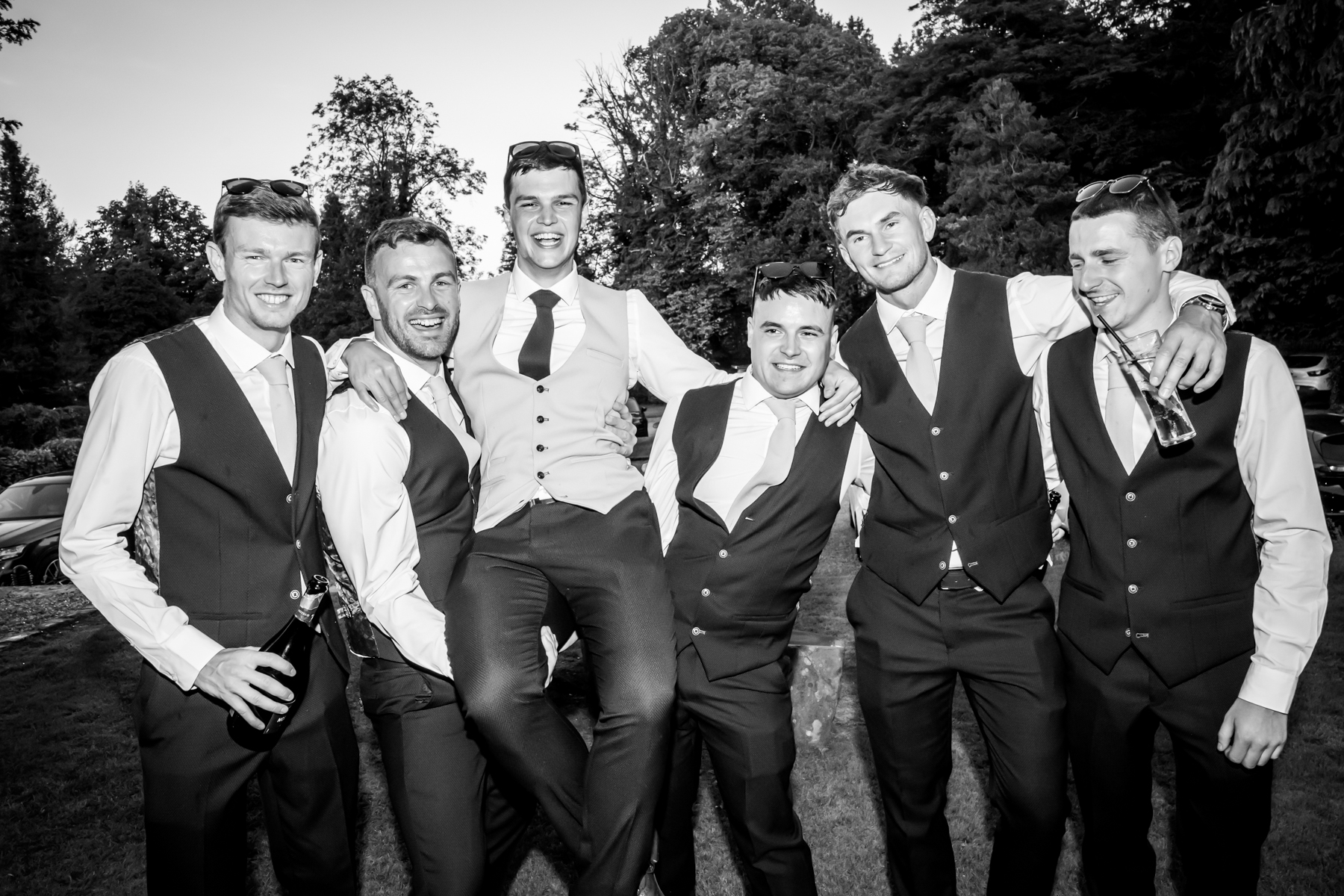 Group of men in suits celebrating outdoors.