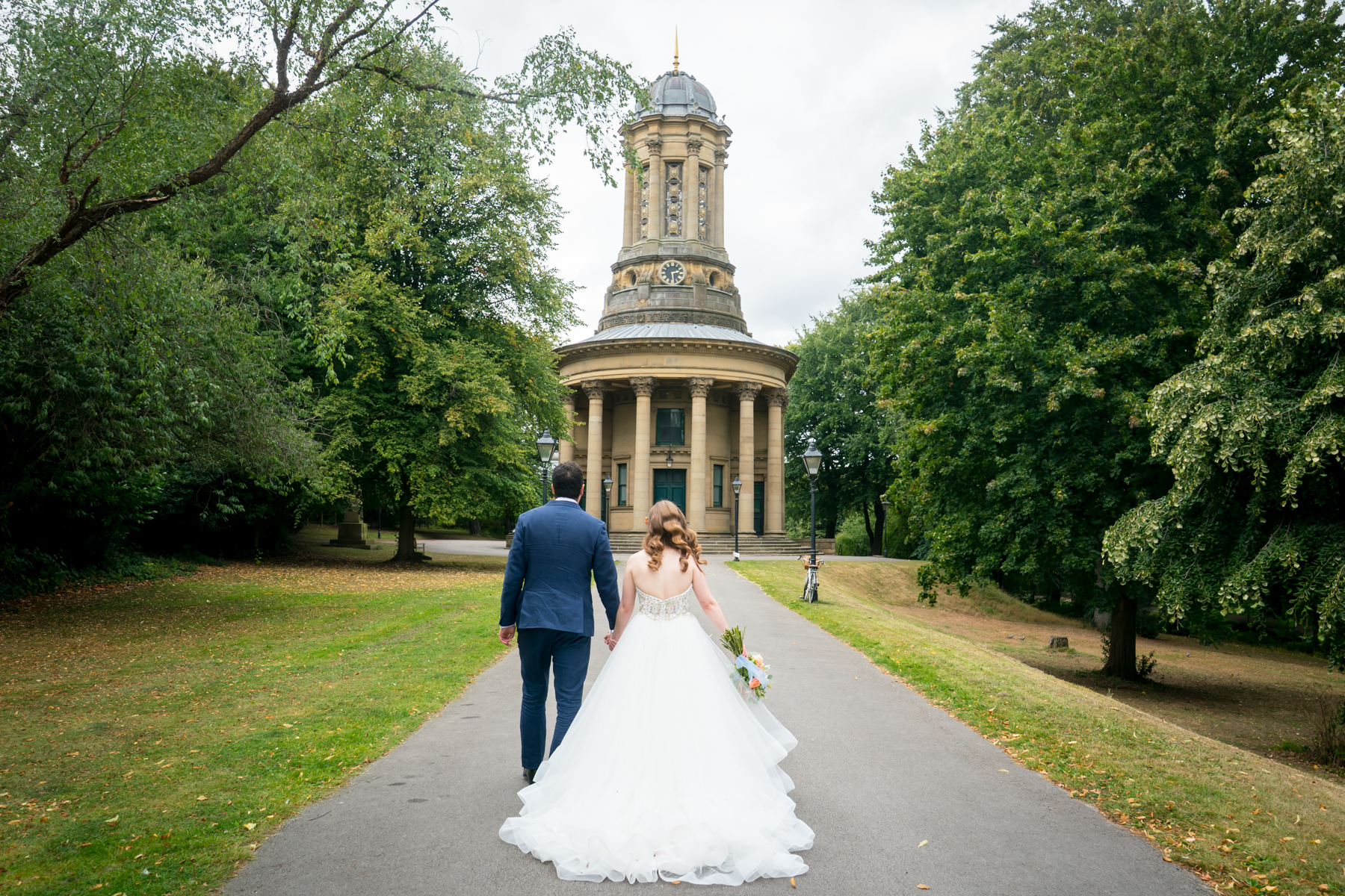 Bride and groom walking towards historic building.