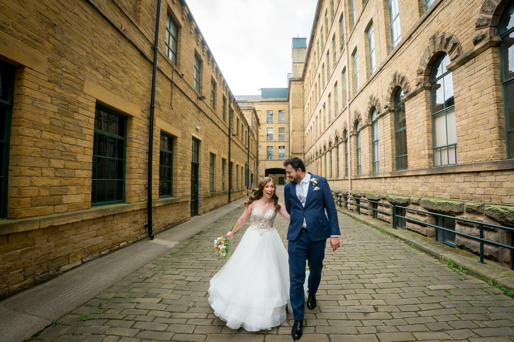 Bride and groom walking in historic courtyard.