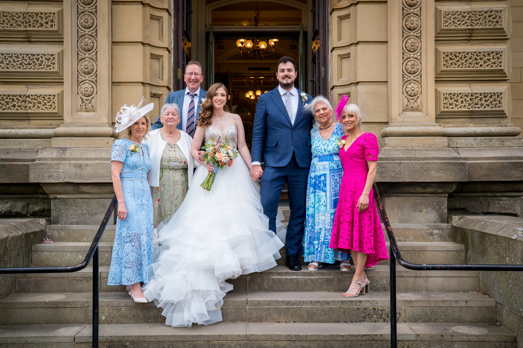 Bride, groom and family outside building steps.