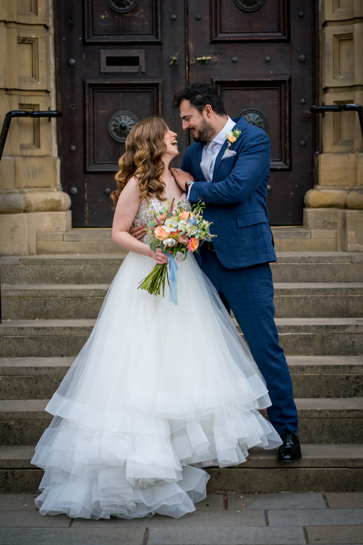 Happy couple smiling on wedding day stairs