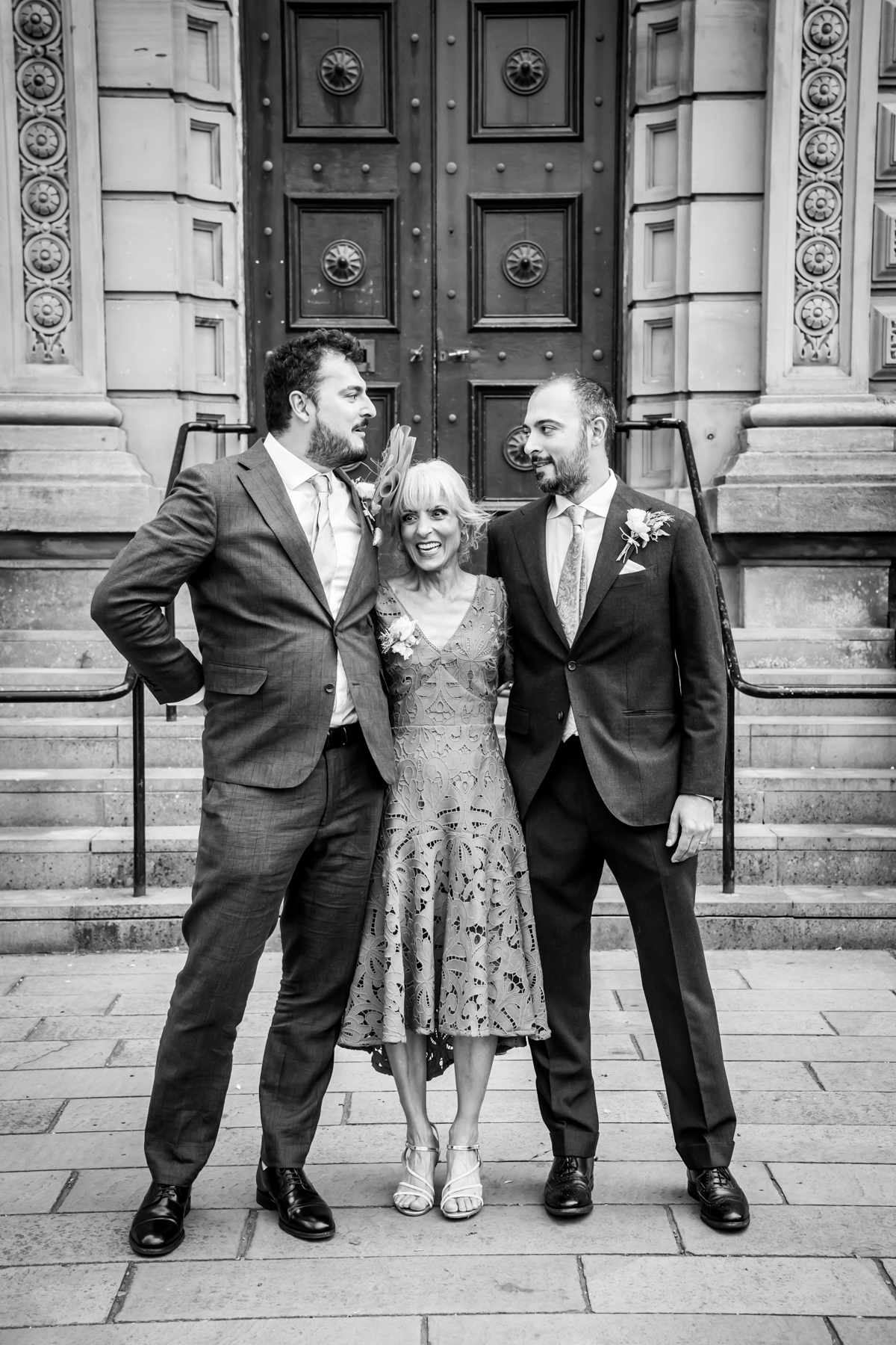 Three people smiling in front of ornate doors.