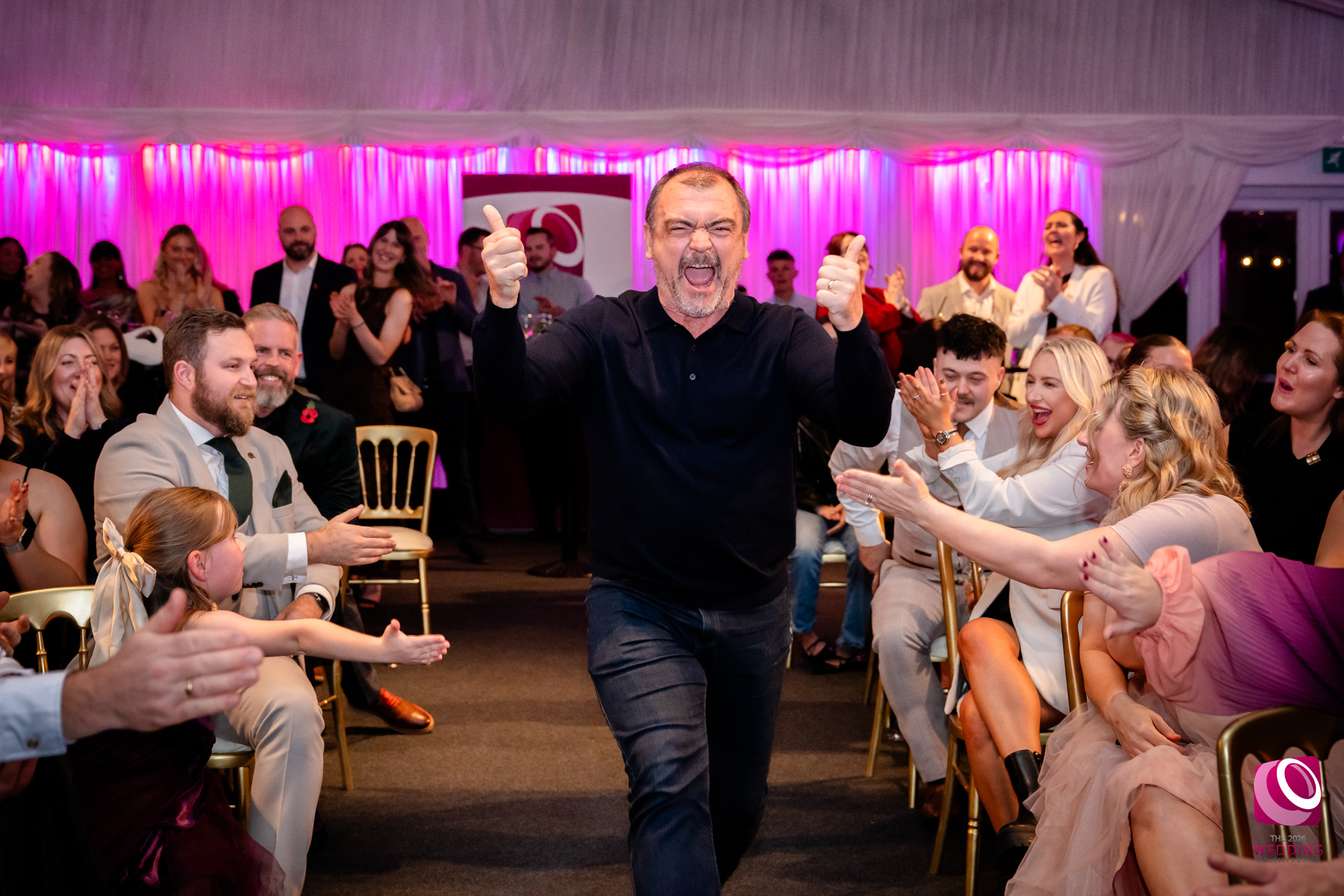 Man celebrating, crowd clapping at event, joyous atmosphere.