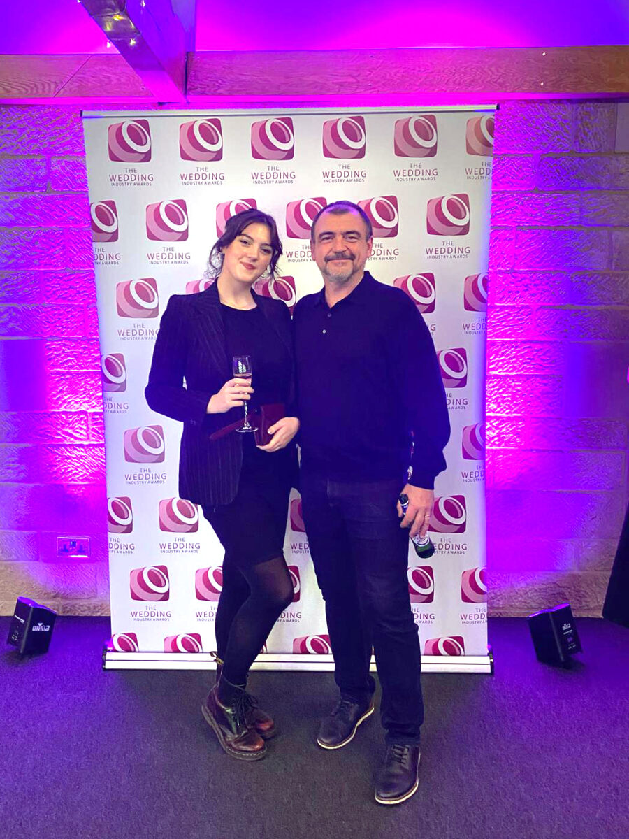 Two people smiling at wedding awards event.