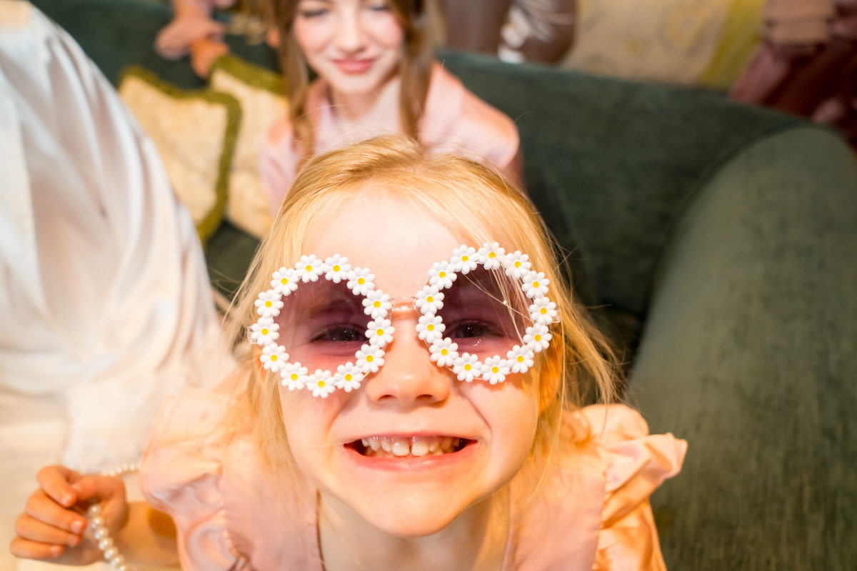 Child wearing daisy-shaped sunglasses, smiling widely.
