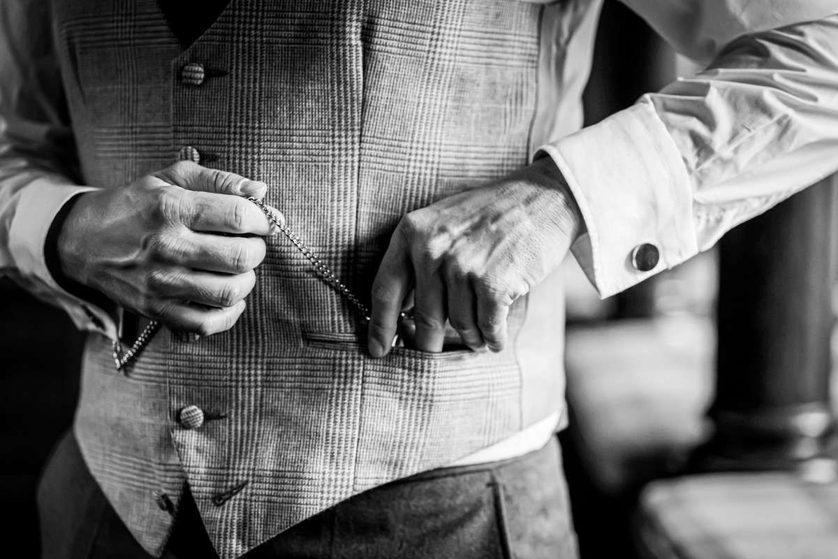 Man adjusting his waistcoat with a pocket watch.