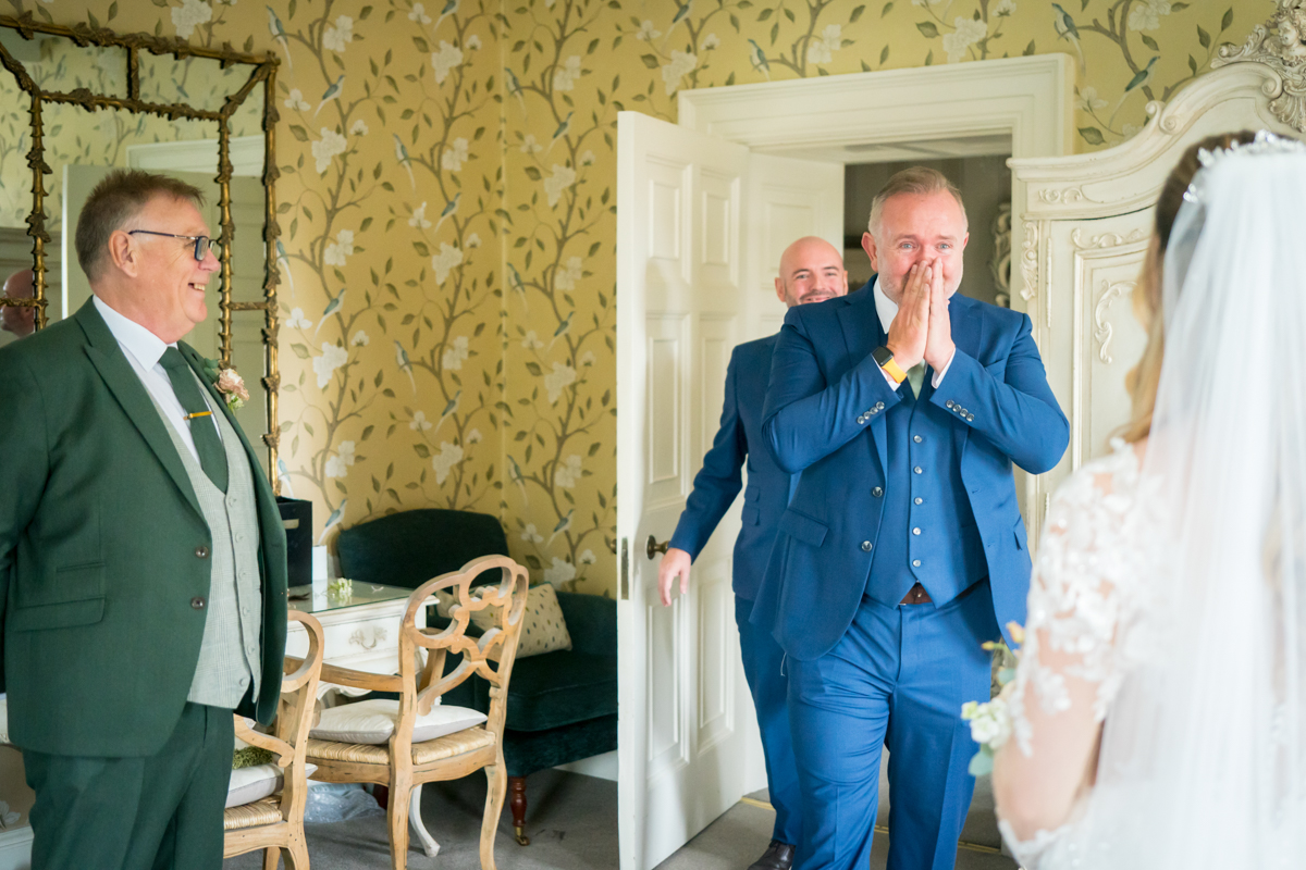 Groom and family emotional seeing bride in dress.