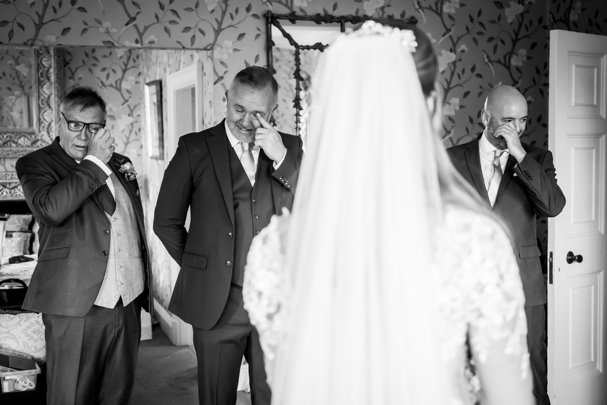 Emotional men reacting to bride entering room