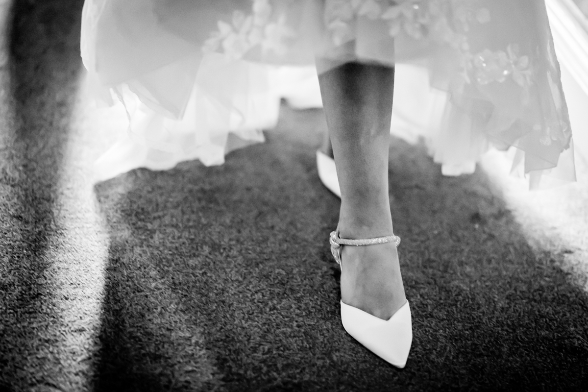 Bride's feet wearing elegant white shoes.